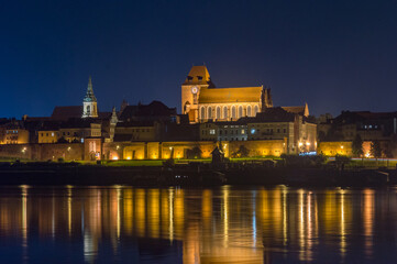 Fototapeta na wymiar Old town of Torun with Church of St. John the Baptist and St. John the Evangelist. View on vistula river at night.