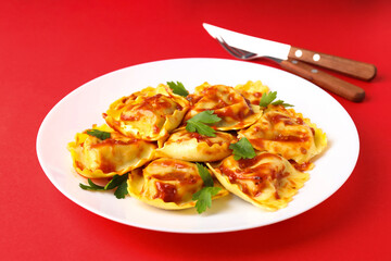 Delicious food concept with ravioli on red background