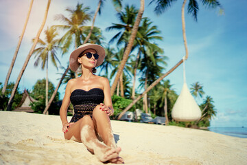 Vacation on the seashore.Young woman in hat and swimsuit on the beautiful tropical white sand beach resort.