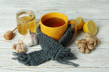 Concept of treatment colds with honey and garlic on white wooden background