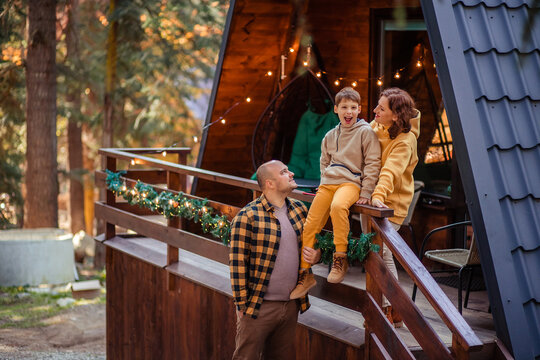 Happy Family Of Travelers In The Forest In The Mountains Near The Wooden Chalet House