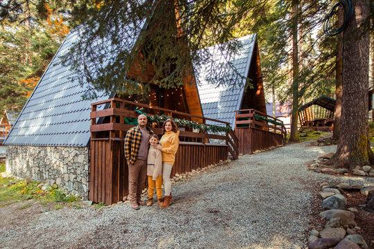Happy family of travelers in the forest in the mountains near the wooden chalet house