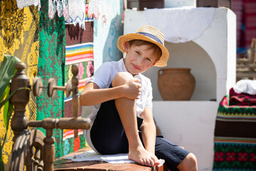 Obraz na płótnie Canvas Belarusian or Ukrainian boy in a straw hat against the background of the stove. Country child.
