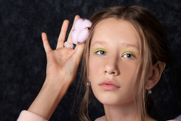 Portrait of a teenage girl in pink clothes on a dark background.