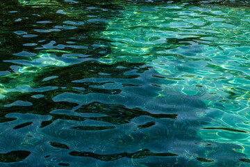 Fototapeta na wymiar Turquoise water surface with a bottom visible through the water. Background screensaver.