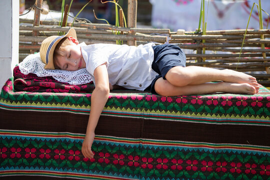 A Belarusian or Ukrainian boy sleeps on towels. Little ethnic boy is sleeping.