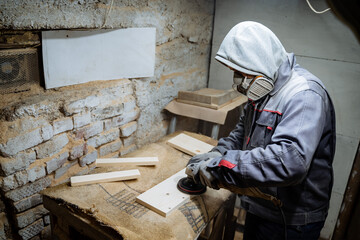 A woodworking master is working on a bar. Surface grinding. Crafting in the carpentry workshop