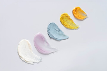 Different cosmetic smears on a light beige background.