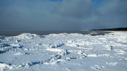 winter landscape by the sea, snowy pieces of ice by the sea, dunes covered with a white layer of shining snow