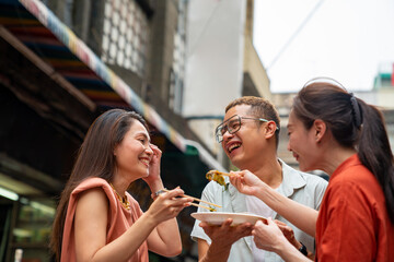 Group of Asian woman and LGBTQ people friends tourist enjoy eating traditional street food fried...