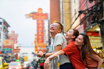Group of Asian people tourist walking down street and shopping together at Chinatown in Bangkok city, Thailand. Male and female friends enjoy outdoor lifestyle travel and eating street food at night