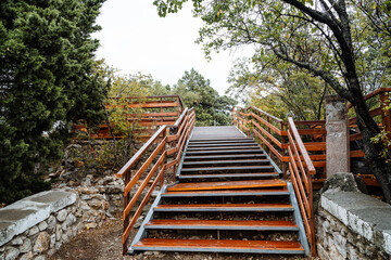 A bright orange metal staircase going up, a park stretches around it. Descent to the river.