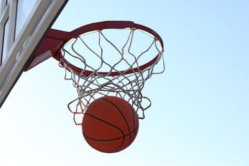 Basketball ball and hoop with net outdoors on sunny day