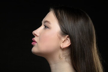 Profile of a young female model with perfect sensual lips and closed eyes on a black background....