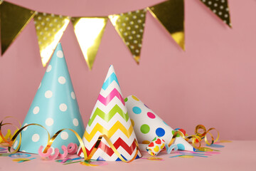Fototapeta na wymiar Colorful party hats and festive items on pink background. Space for text