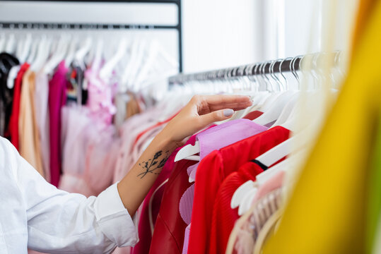 Cropped View Of Tattooed Woman Reaching Hanger While Choosing Clothes