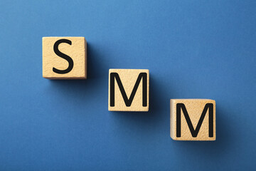 Wooden cubes with word SMM on blue background.