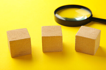 Wooden cubes with word SMM and magnifying glass on yellow background.