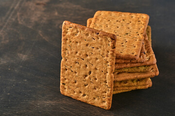 Cracker with flax seeds and oat bran rectangular shape for healthy, dietary and balanced diet on dark wooden background. Snack for proper nutrition.