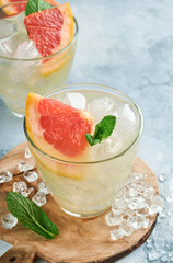 Lemonade drink made from grapefruit, soda water and mint leaves with ice on light blue slate, stone or concrete background. Healthy homemade lemonade or cocktail. Mock up. Top view.