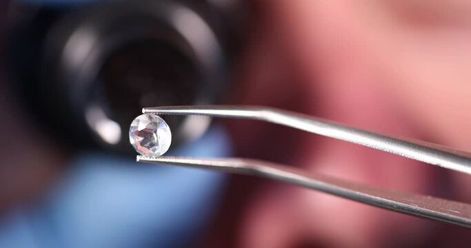 Jeweler holds precious transparent stone in tweezers slow motion 4k movie