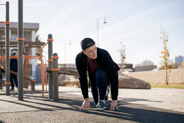 young male sportsman stretching and warm up outdoors in the street