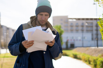 male courier checking the paper documents outdoors, home goods delivery