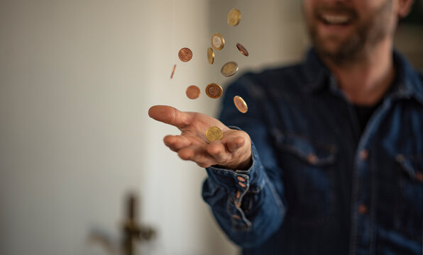 Ein glücklicher Mann schmeißt Münzen in die Luft