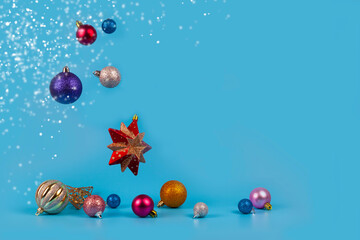Multicolored Christmas balls are falling on a blue background.