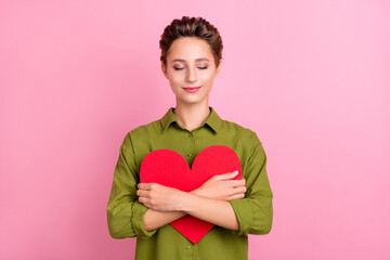 Photo of charming sweet young lady wear green blouse embracing big red heart smiling isolated pink color background