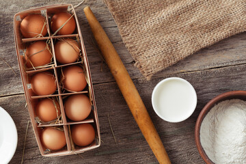 Ingredients for baking - flour, eggs, milk. With rolling pin and pouch. On wooden table
