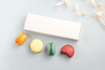 Present box mockup and colorful macarons on a blue background with dry branch
