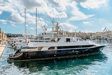 Fototapeta na wymiar Luxury motorboats in Vittoriosa Yacht Marina.Sunny summer day.Holiday high-class lifestyle travel concept.Boat trip in Mediterranean.View of expensive sailing yachts at the pier. Posh deluxe vacation