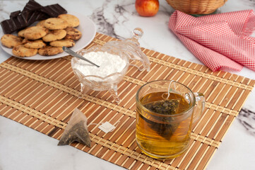 cup of tea with tea bag with plate with chocolate cookies for snack or breakfast