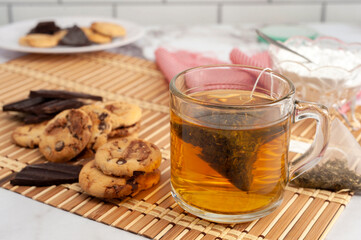 cup of tea with tea bag with plate with chocolate cookies for snack or breakfast