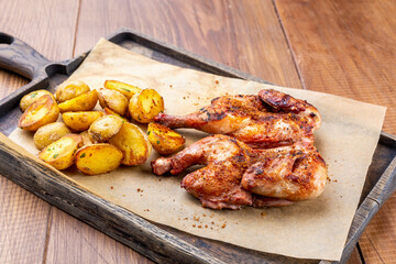 Roast chicken and baked potatoes on wooden board