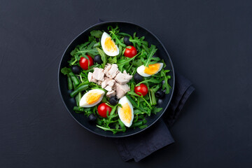 tasty tuna salad in a black bowl on black background