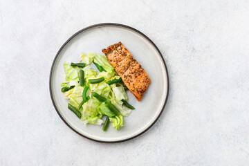 A healthy meal on plate, salmon, green salad, vegetables.