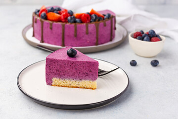 Slice of delicious blueberry cheesecake on white plate, light table