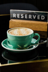 Hot cappuccino, coffee or Americano in blue ceramic cup on black table background.