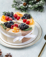 Christmas assorted cake decorated with tangerine, berries and on a white background with a Christmas decoration or winter holidays pastry food concept.