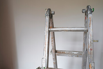 metal ladder in paint with blue rag across the white walls. Painting walls, reconstruction works....