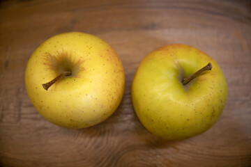 two yellow apples on a wooden tabletop