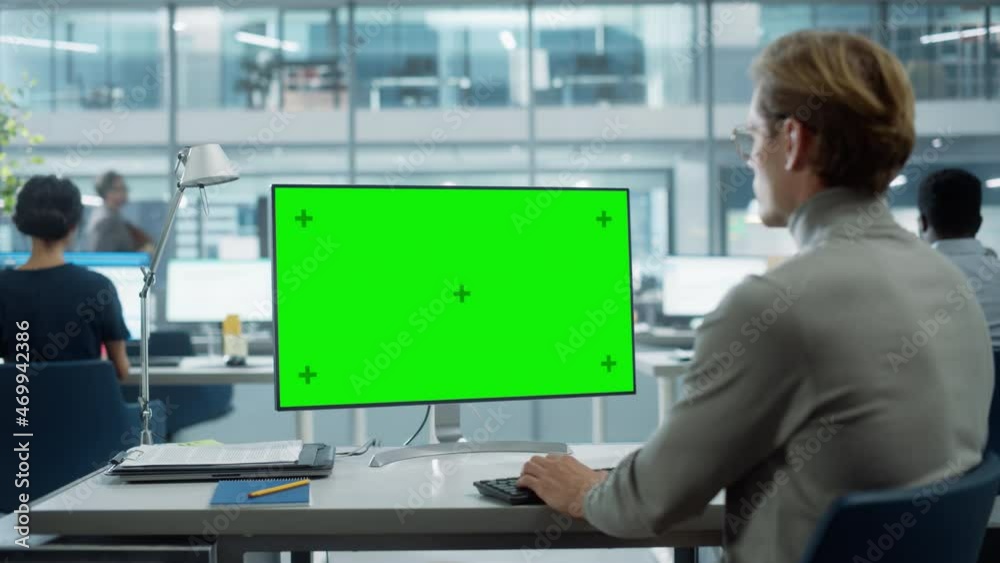 Fototapete Close Up Over the Shoulder Shot of a Businessman Working on Desktop Computer with Chroma Key Green Screen Mock Up Display. Digital Projects Manager Typing Data, Using Keyboard and Mouse.