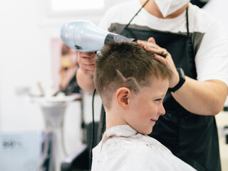 Little boy getting haircut in barbershop
