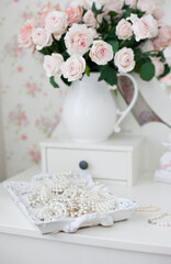 Fototapeta na wymiar Vintage dressing table with pink roses and pearls jewelry