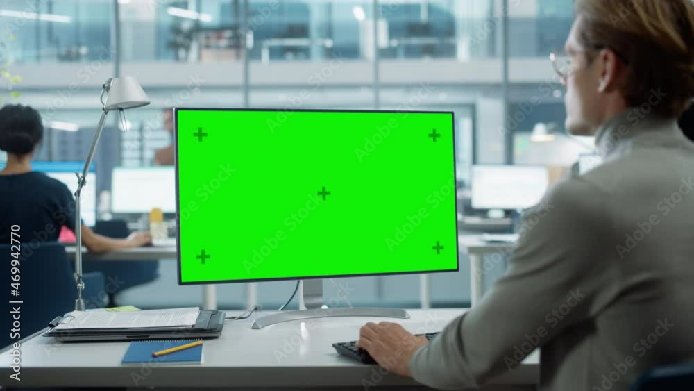 Poster Close Up Over the Shoulder Shot of a Businessman Working on Desktop Computer with Chroma Key Green Screen Mock Up Display. Digital Projects Manager Typing Data, Using Keyboard and Mouse.