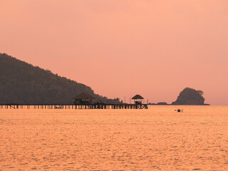 Scenic view of colorful sunset at peaceful sea with long wooden pier landmark over water of tropical paradise island. Koh Mak Island, Trat, Thailand.