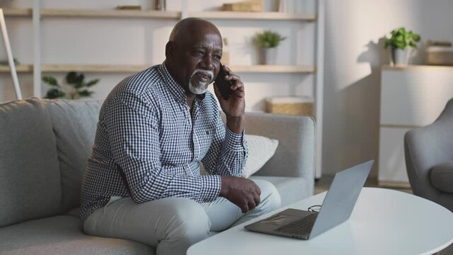 Freelance and retirement. Senior african american man consulting clients talking on cellphone and working on laptop