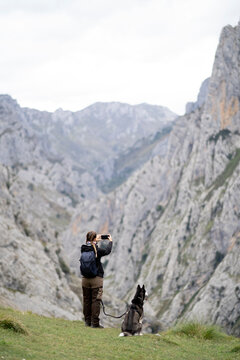 Female hiker with Husky taking picture of mountains